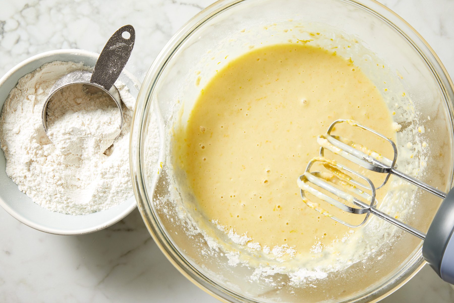 Overhead shot of another bowl combine orange juice; sugar; butter; eggs; orange zest; salt; yeast mixture and 2 cups flour; beat on medium speed until smooth; marble surface;
