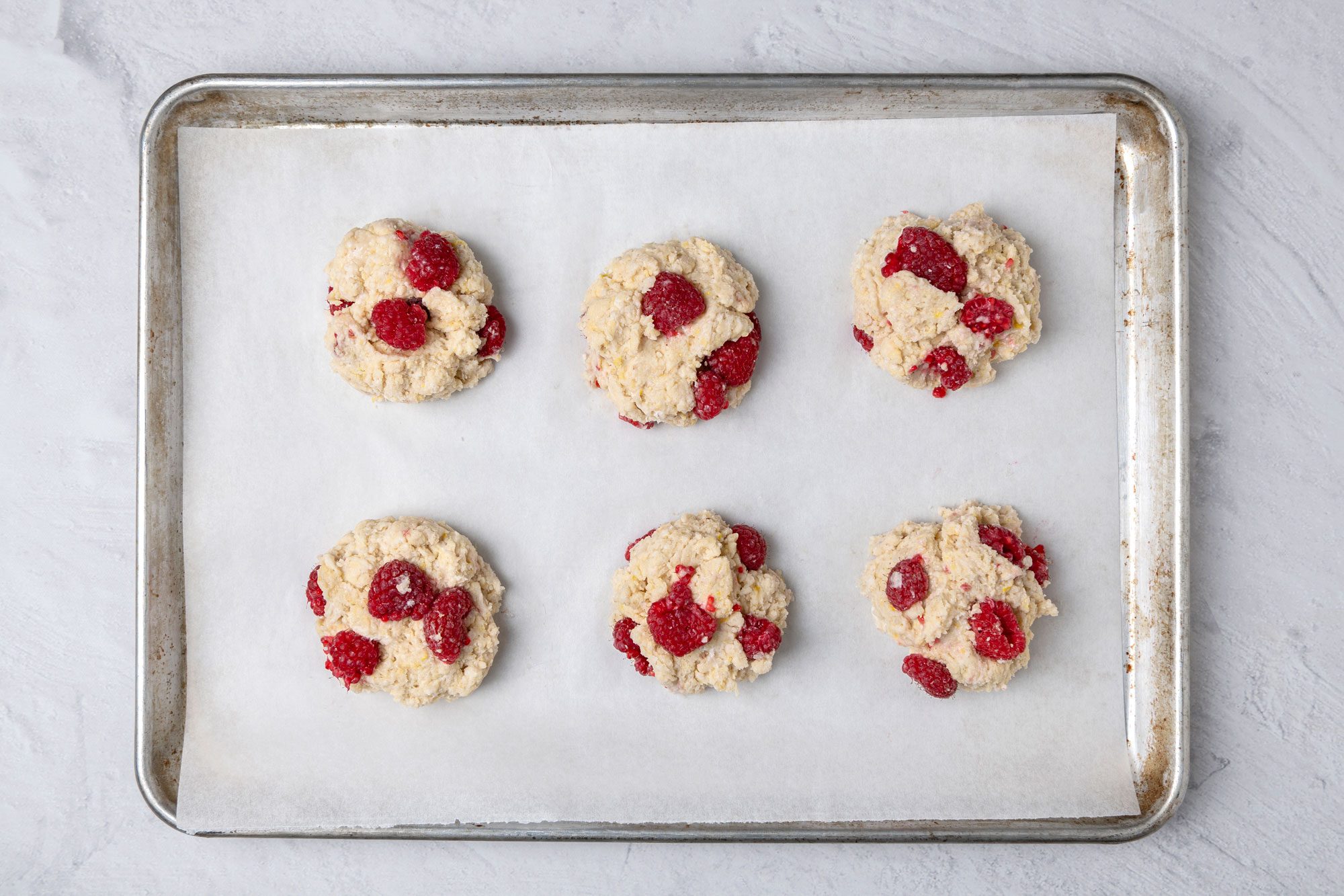 Overhead shot of baking sheet; Drop by 1/2 cup scoops 2 inch apart onto a greased baking sheet; Bake at 400 degree for 15-18 minutes or until lightly browned; marble surface;