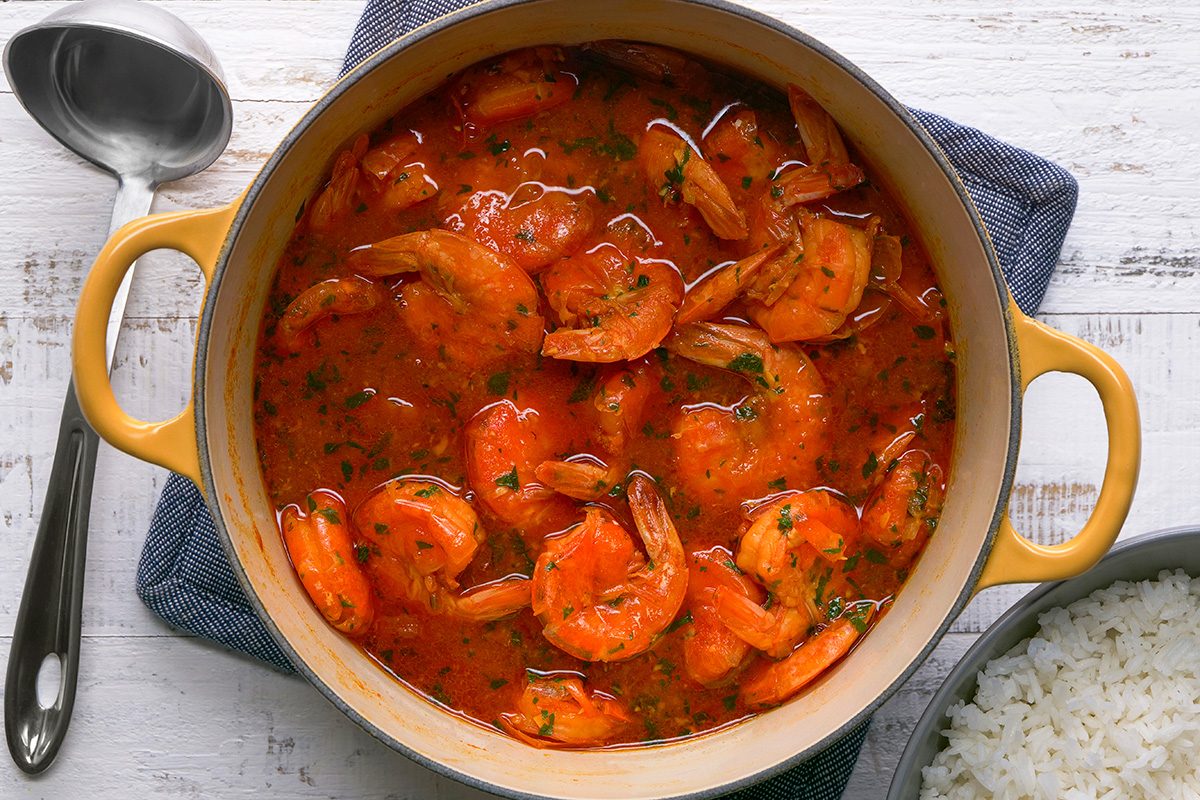A pot of food on a table, prepared with ketchup and parsley, awaiting serving alongside hot cooked rice.