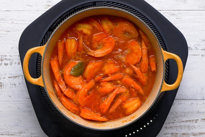 A pot of food on a table, prepared with ketchup and parsley, awaiting serving alongside hot cooked rice.