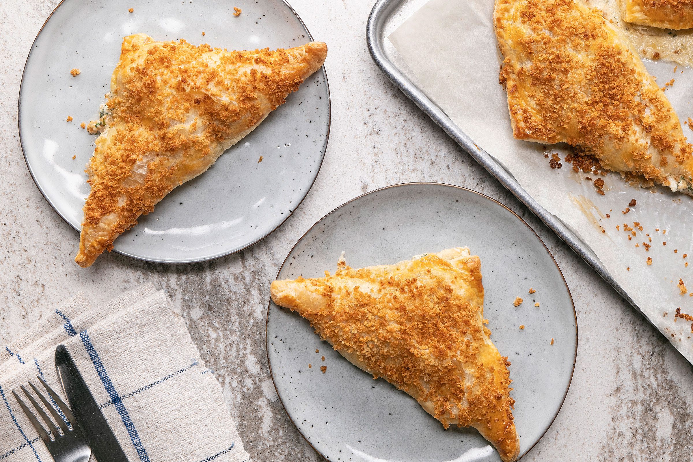 Shrimp Puff Pastry Triangles on a parchment-lined baking sheet with cutlery placed on side.