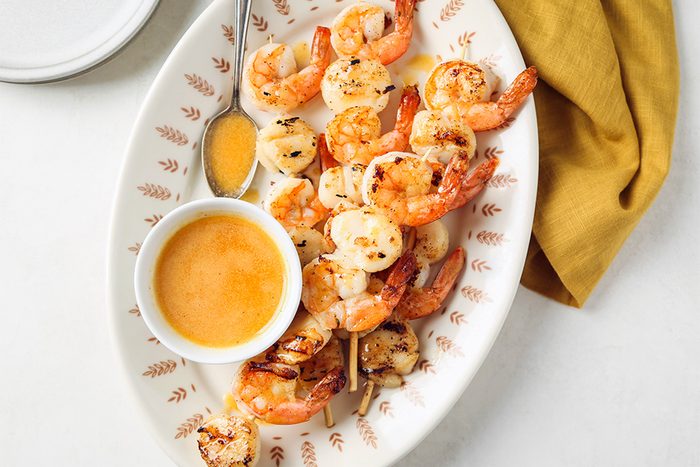 Delicious grilled shrimp skewers with a vibrant dipping sauce, presented on a rustic surface.