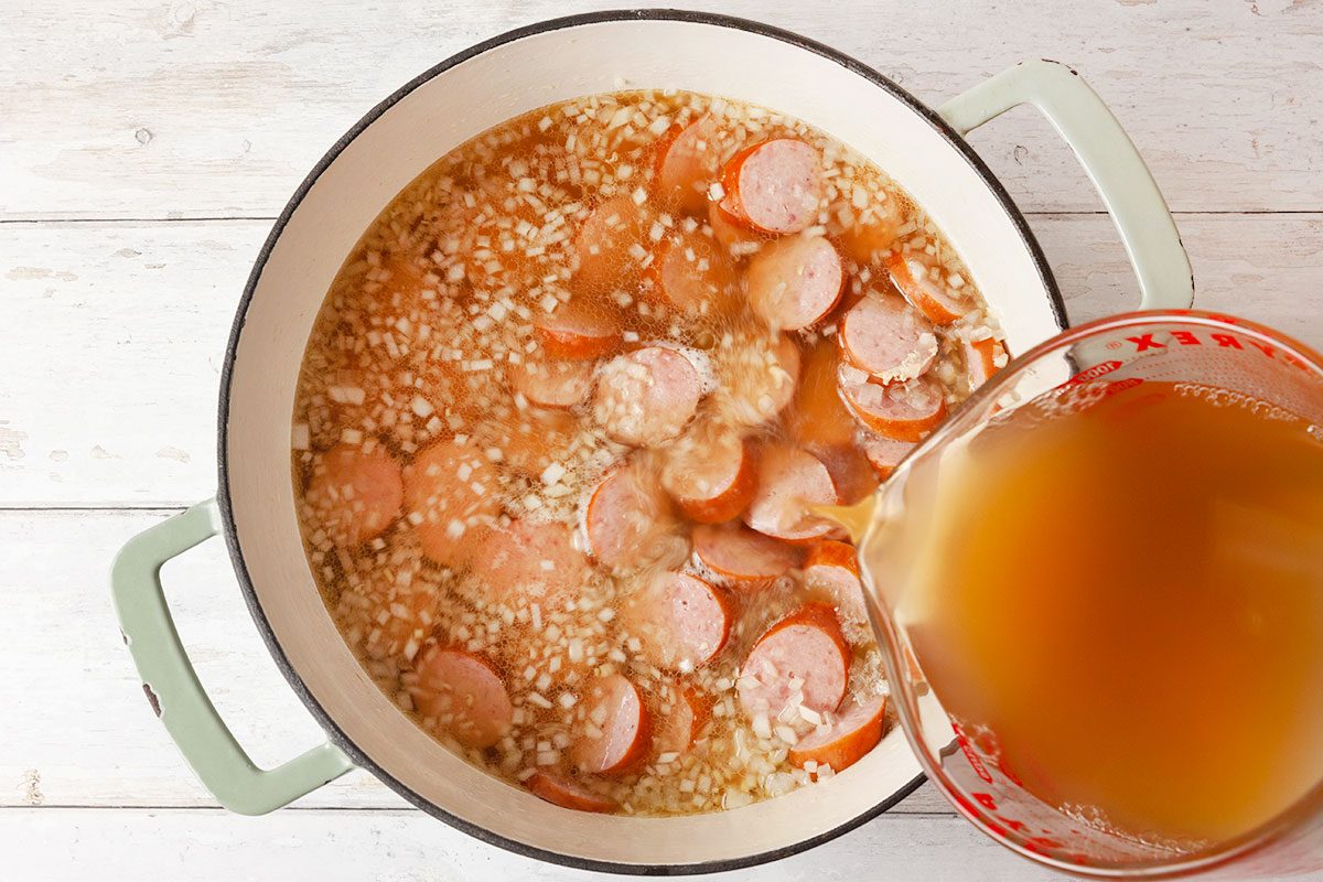 smoked sausage, chopped onion, and 6 cups of broth in a stockpot.