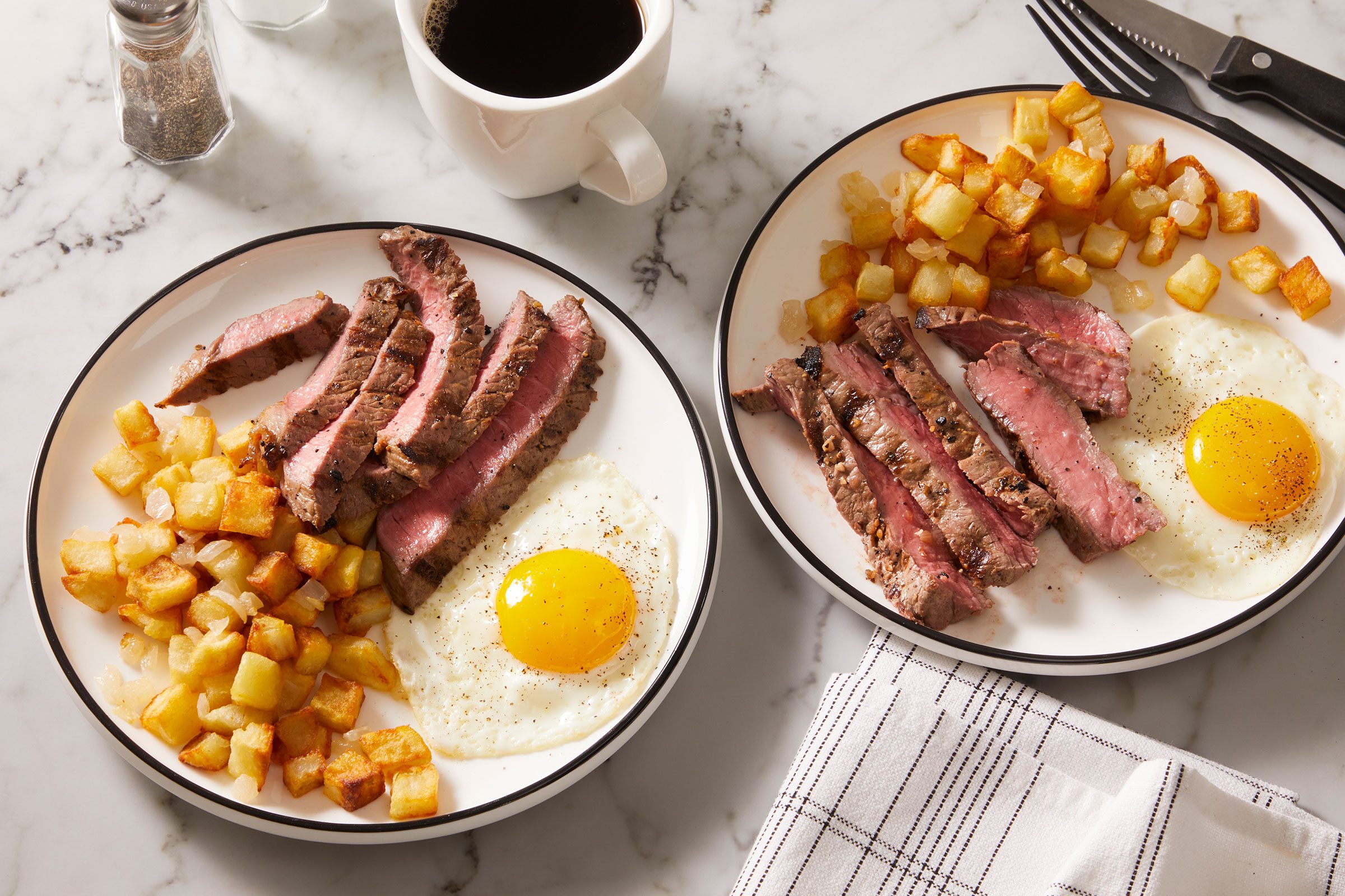 Served some sliced steak with the eggs and potatoes in two white plate with a beverage on side.