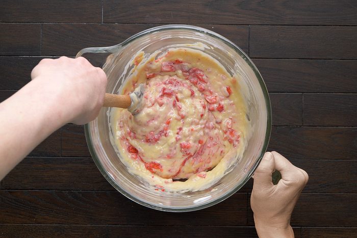 Overhead shot of a creamy batter with bits of red strawberries mixed in