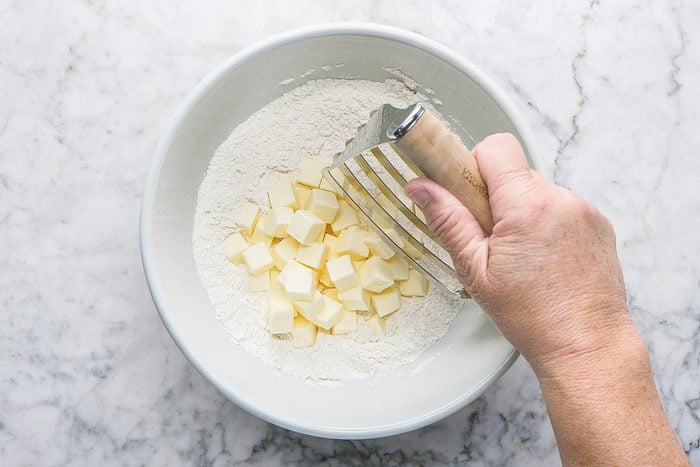 using a pastry blender to cut cold butter into the flour