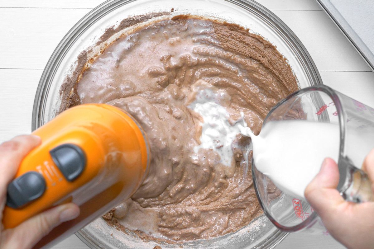 whisking the batter mixture while milk is being added