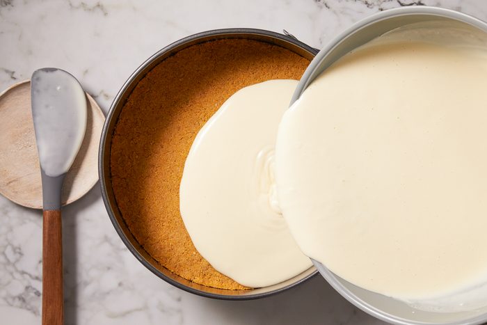 cheesecake filling being poured over crust
