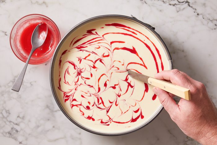 raspberry swirl being mixed with cheesecake filling