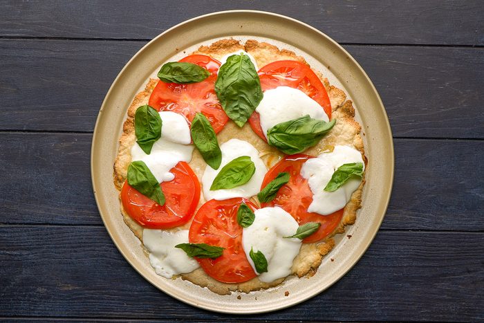 Pizza topped with basil leaves