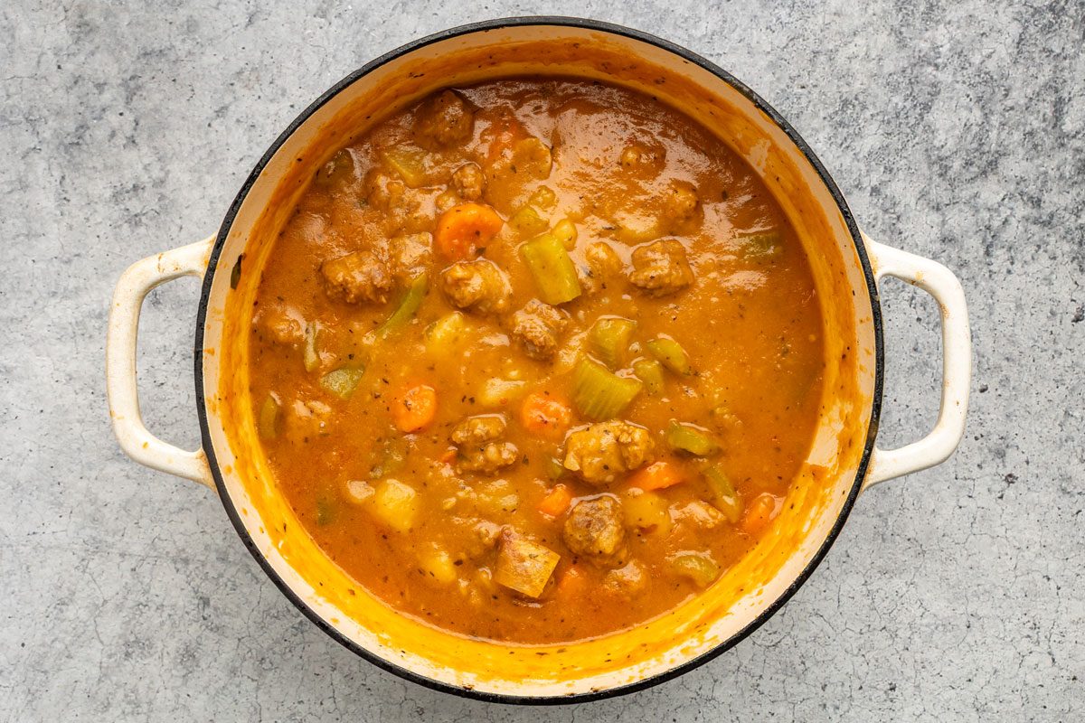 Overhead shot of the same dutch oven; Combine cornstarch and cold water until smooth; gradually stir into stew; Bring to a boil; cook and stir for 2 minutes or until thickened; on a grey marble surface;