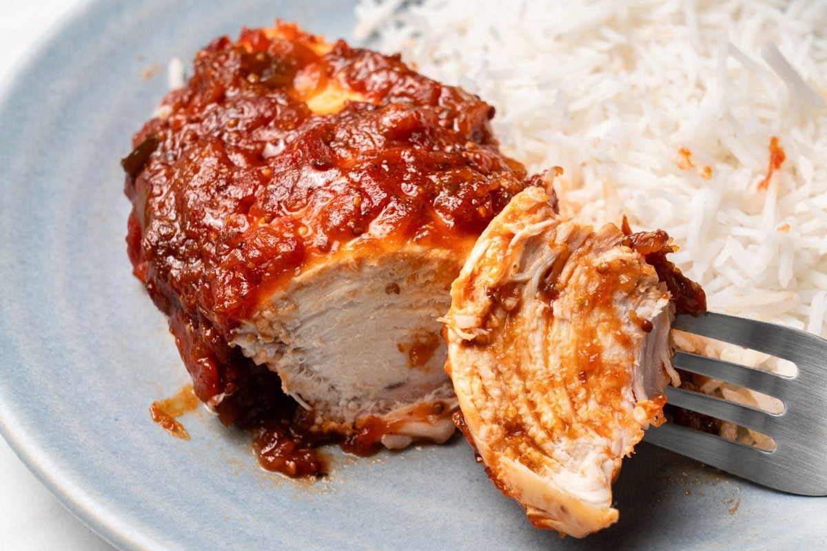 Closeup shot of Chicken Picante served with rice on two light blue ceramic plates; all set on a marble surface;