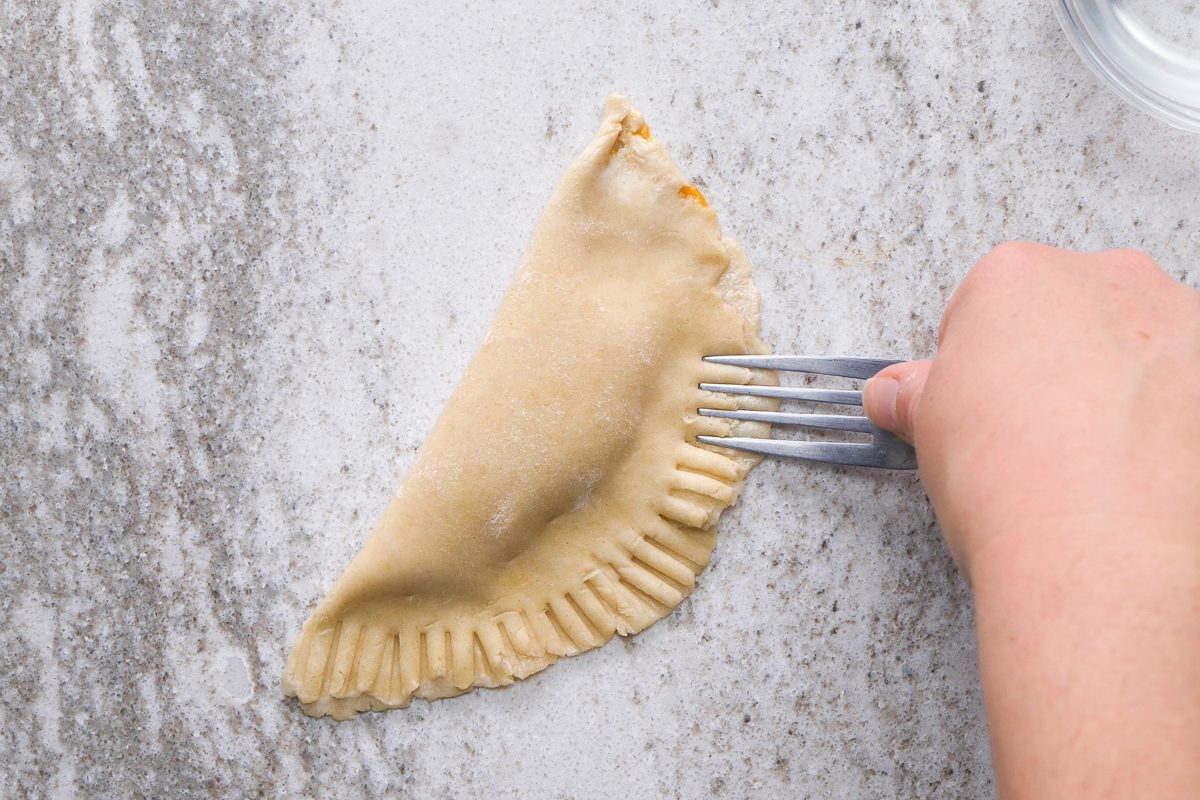 Pressing the edges of dough together with a fork to seal