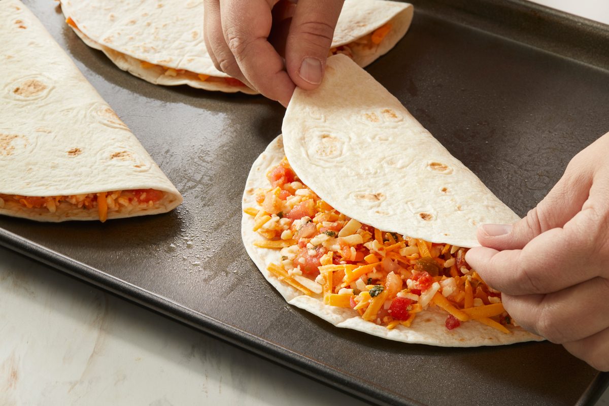 folding tortillas in half with salsa and cheese filling