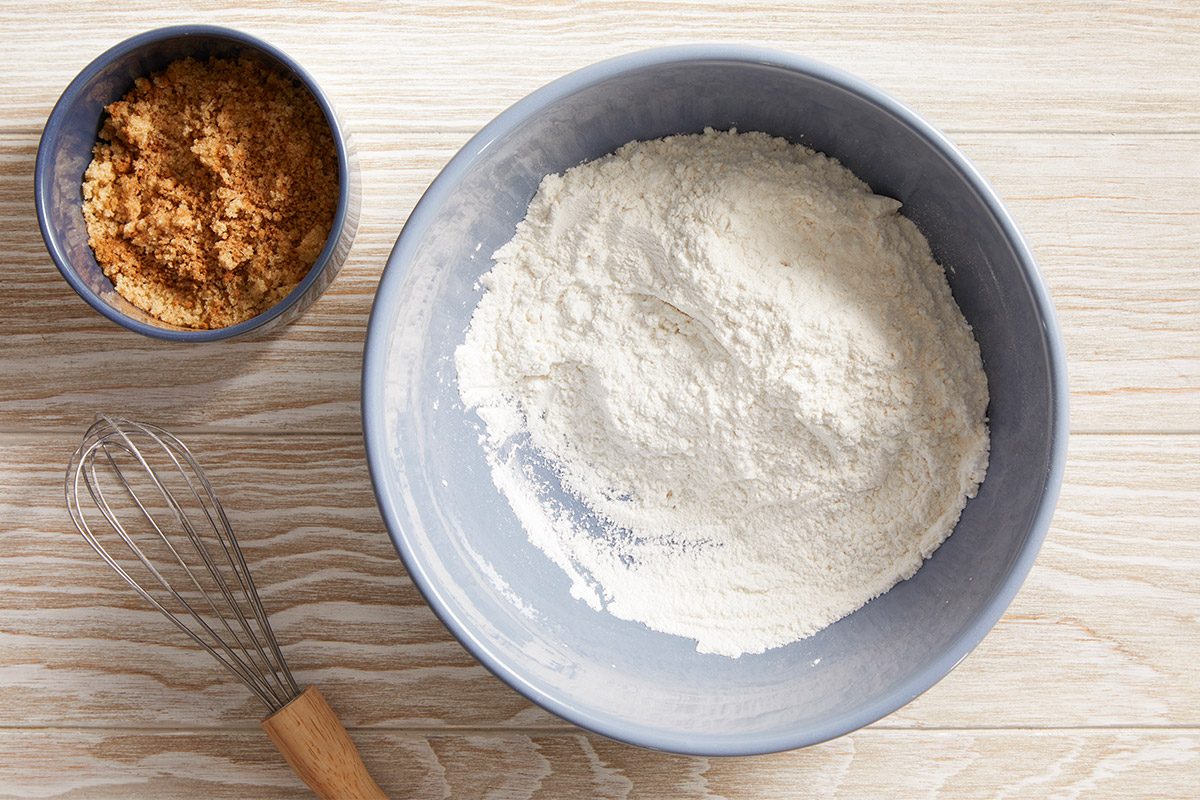 Overhead view of dry ingredients in a bowl with whisk on the side, clean setup before blending.