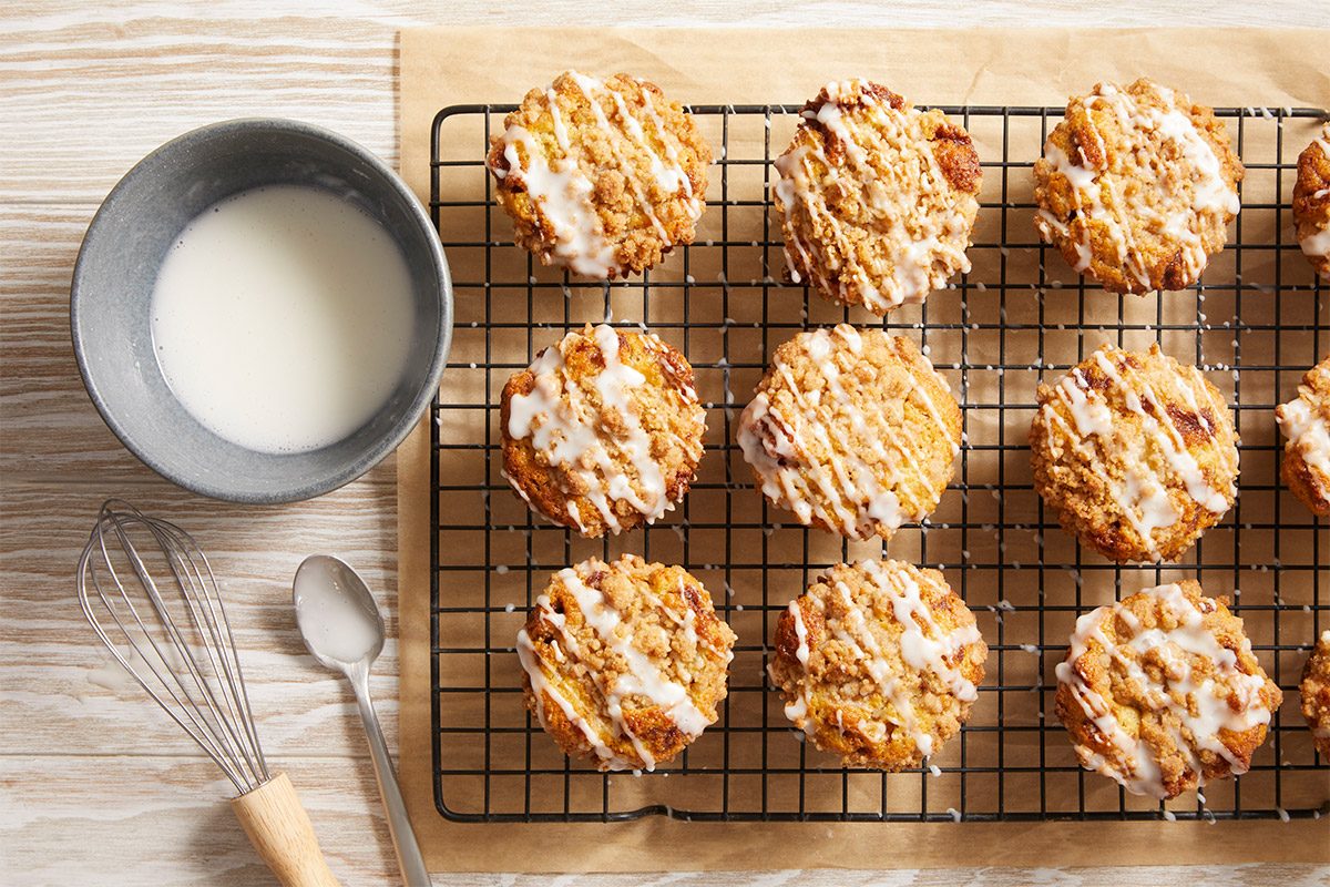 Overhead image of golden muffins cooling on a wire rack, drizzled with glaze