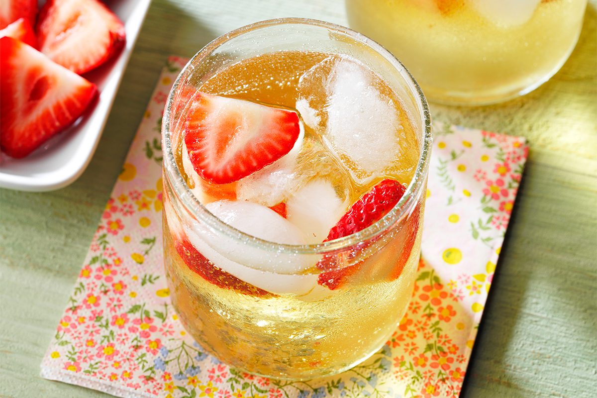 Top view of Mock Champagne Punch kept on top of a table coaster next to garnishes on a green table.