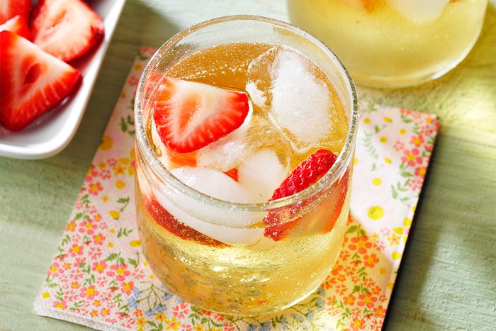 Top view of Mock Champagne Punch kept on top of a table coaster next to garnishes on a green table.