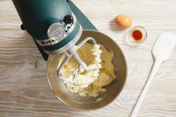 butter and sugar being creamed together in a bowl next to an egg and vanilla extract