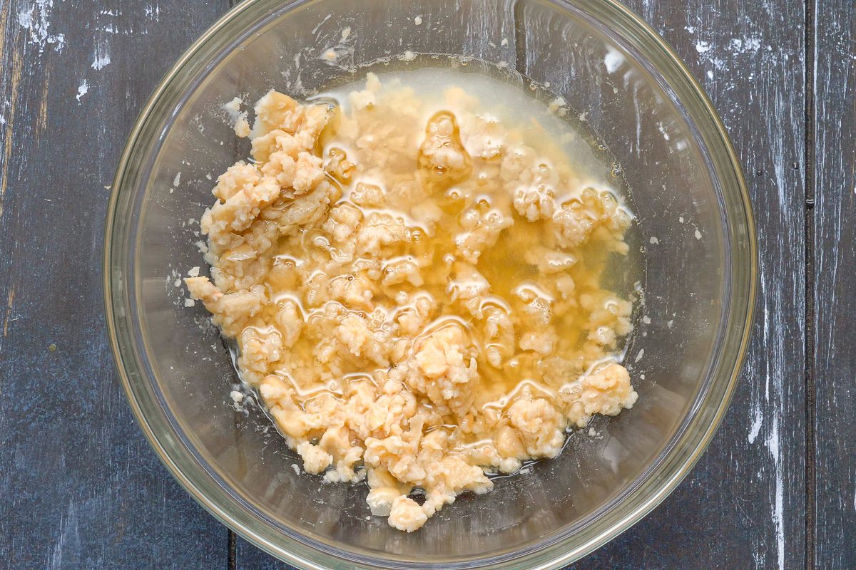 chicken broth added to mashed cannellini beans in a bowl