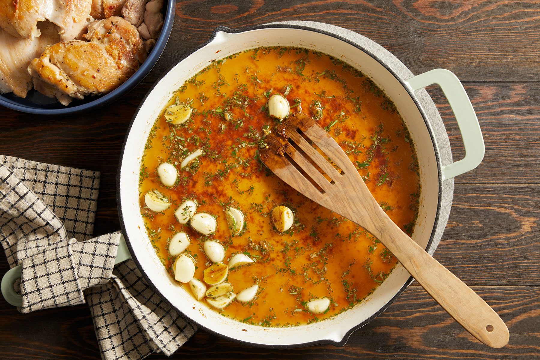 Bringing chicken stock, rosemary and thyme to a boil in a pan.