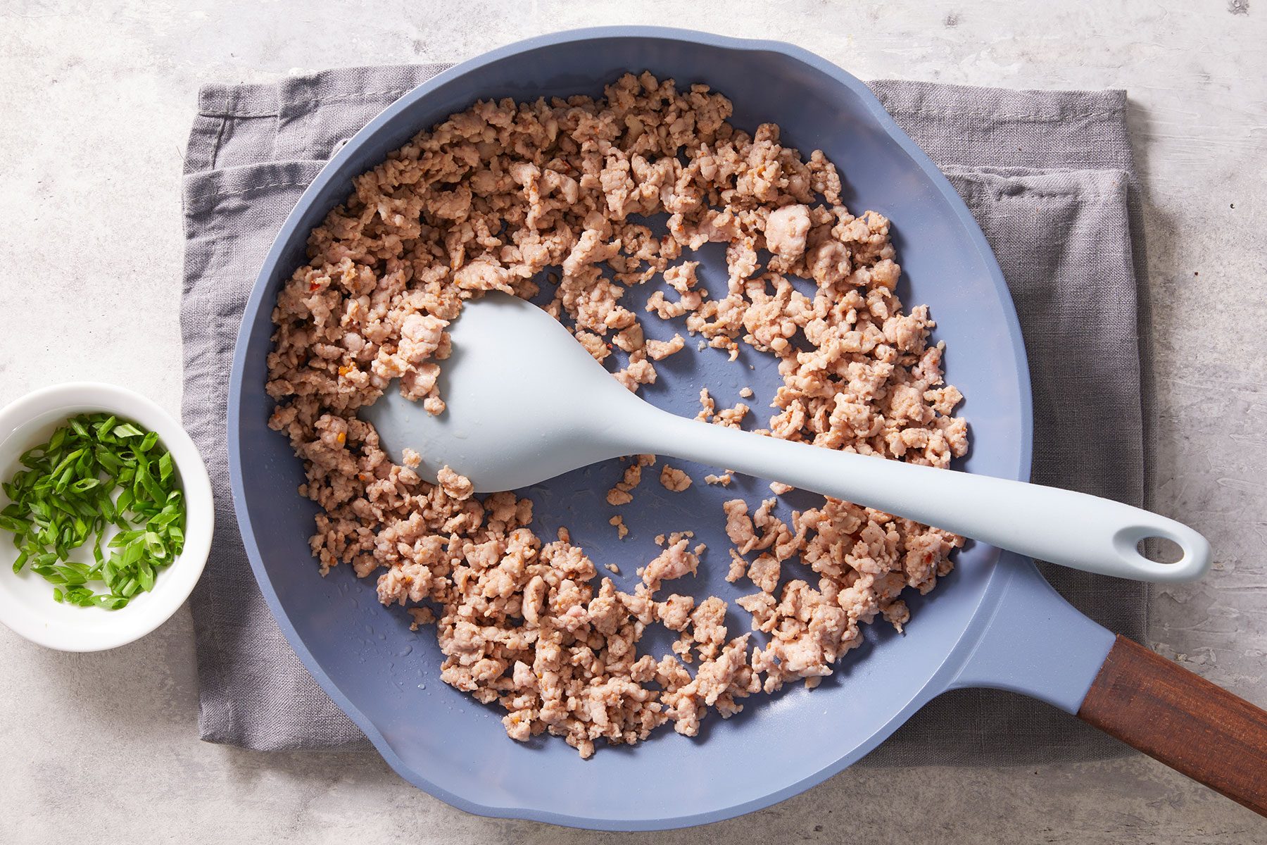 Cooking sausage in a large skillet over medium heat until it’s no longer pink and breaking it into crumbles as it cooks. Minced chives in a small bowl kept on side.