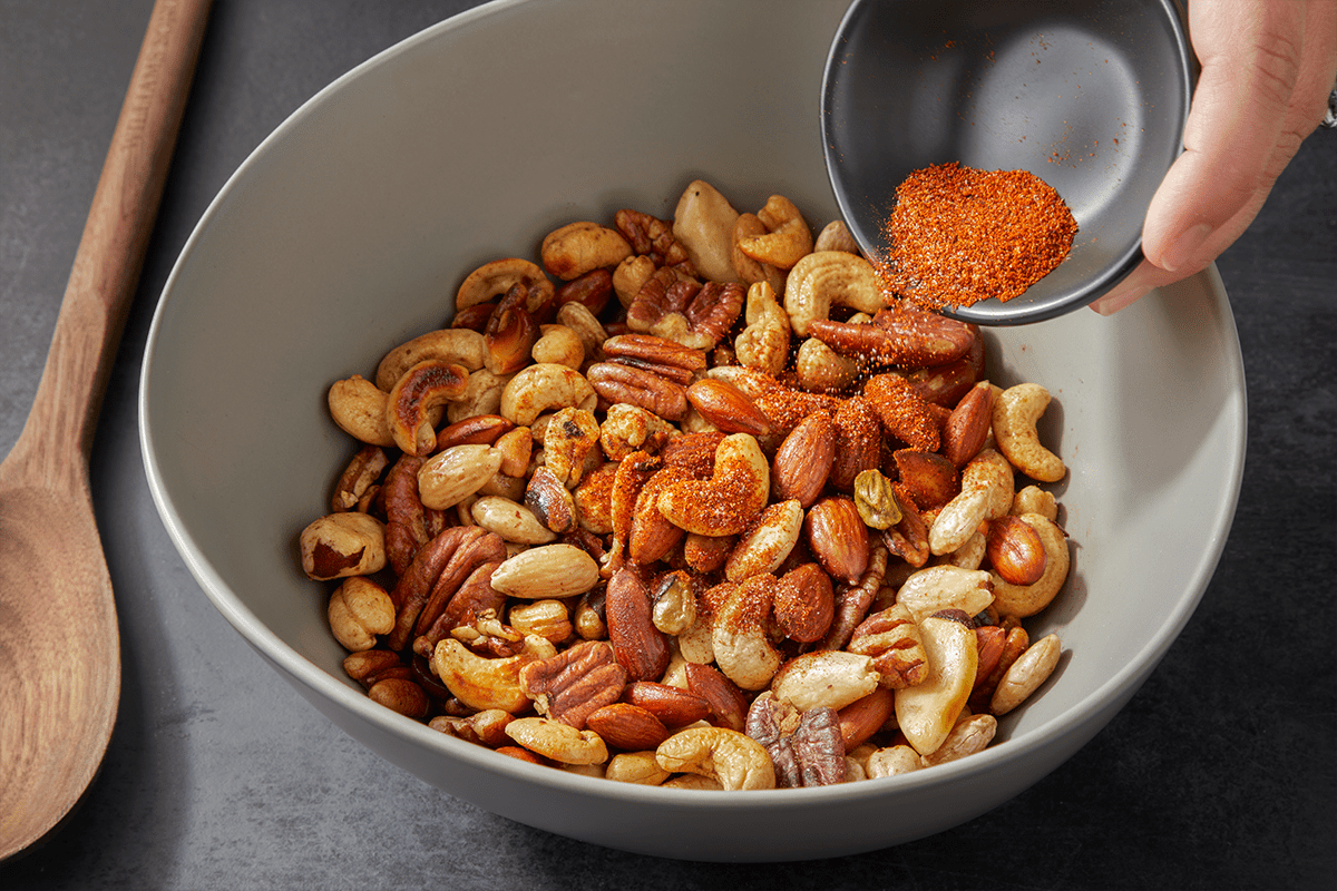 Sprinkling spice over buttered nuts