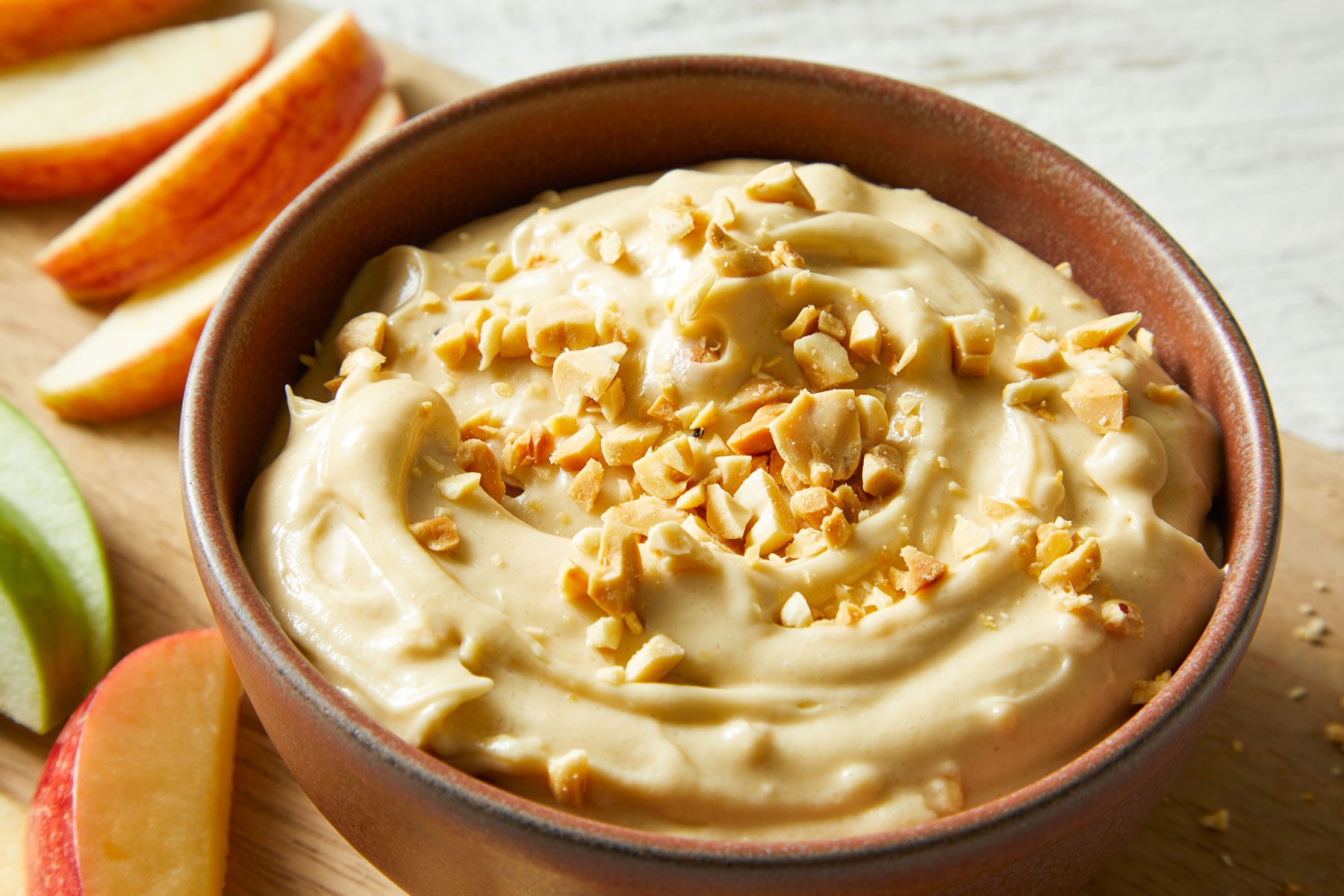 Taffy Apple Dip in a bowl with some fruit slices kept on side.
