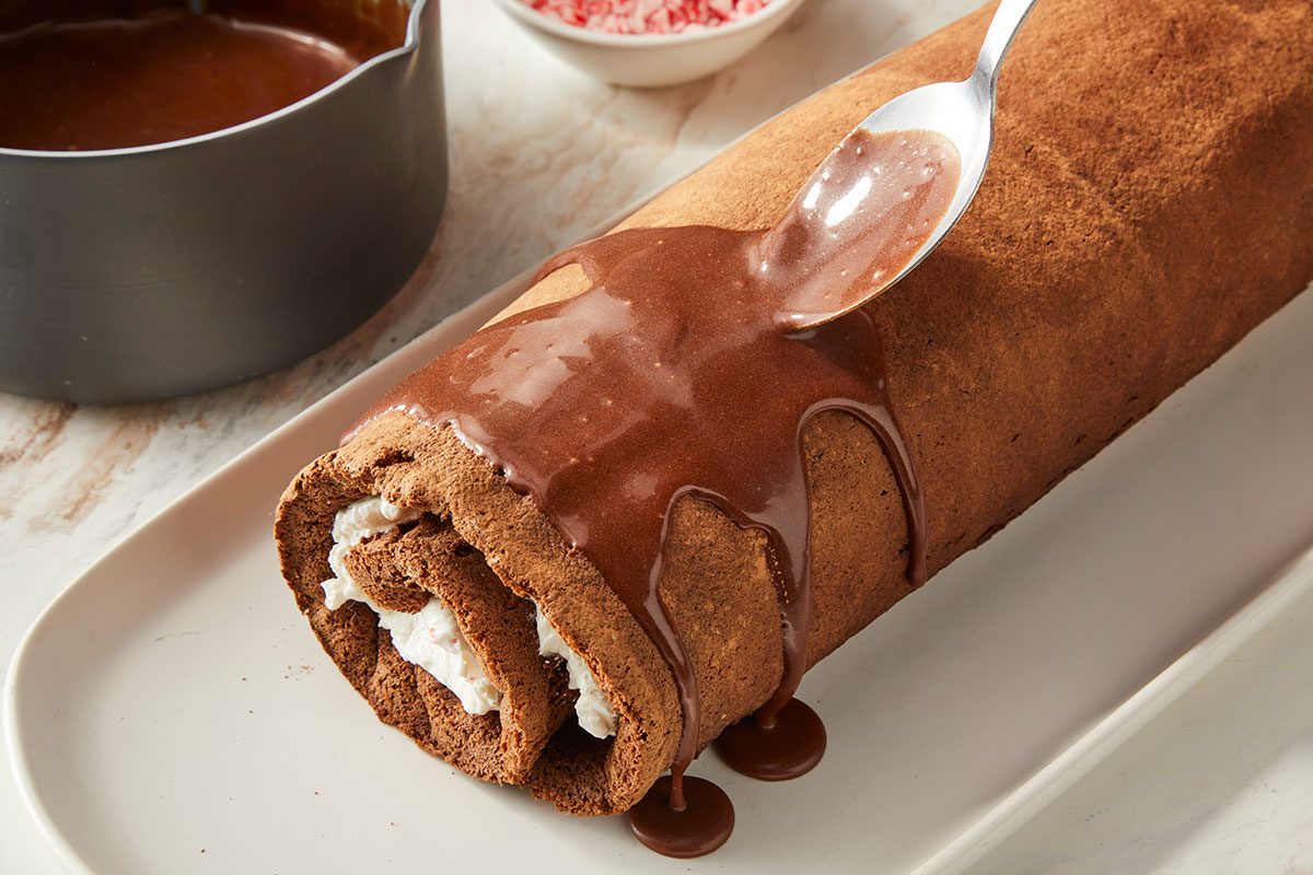 spreading glaze over chilled cake; bowl of peppermint candies on the side