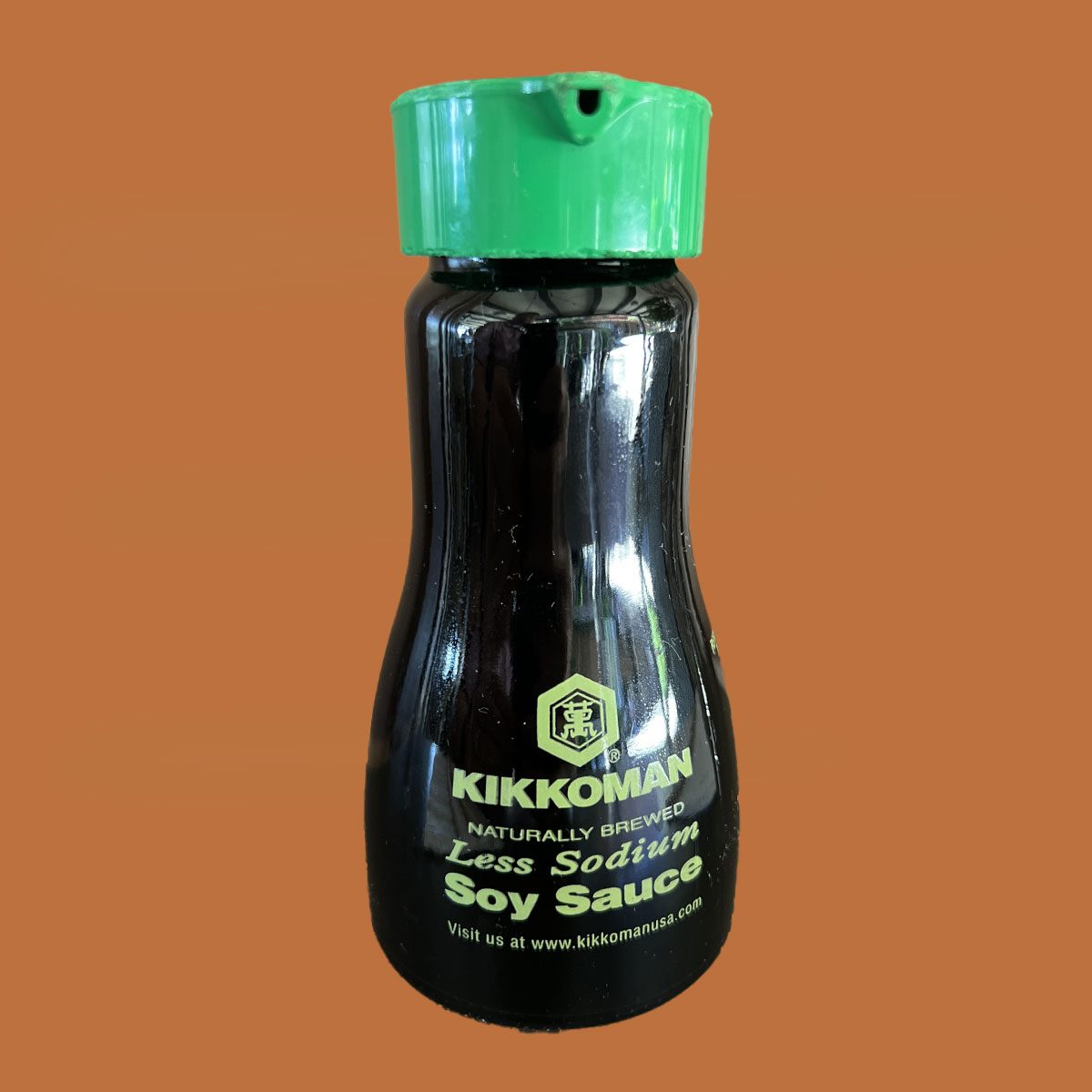 Close-up of Kikkoman Less Sodium Soy Sauce bottle with green cap
