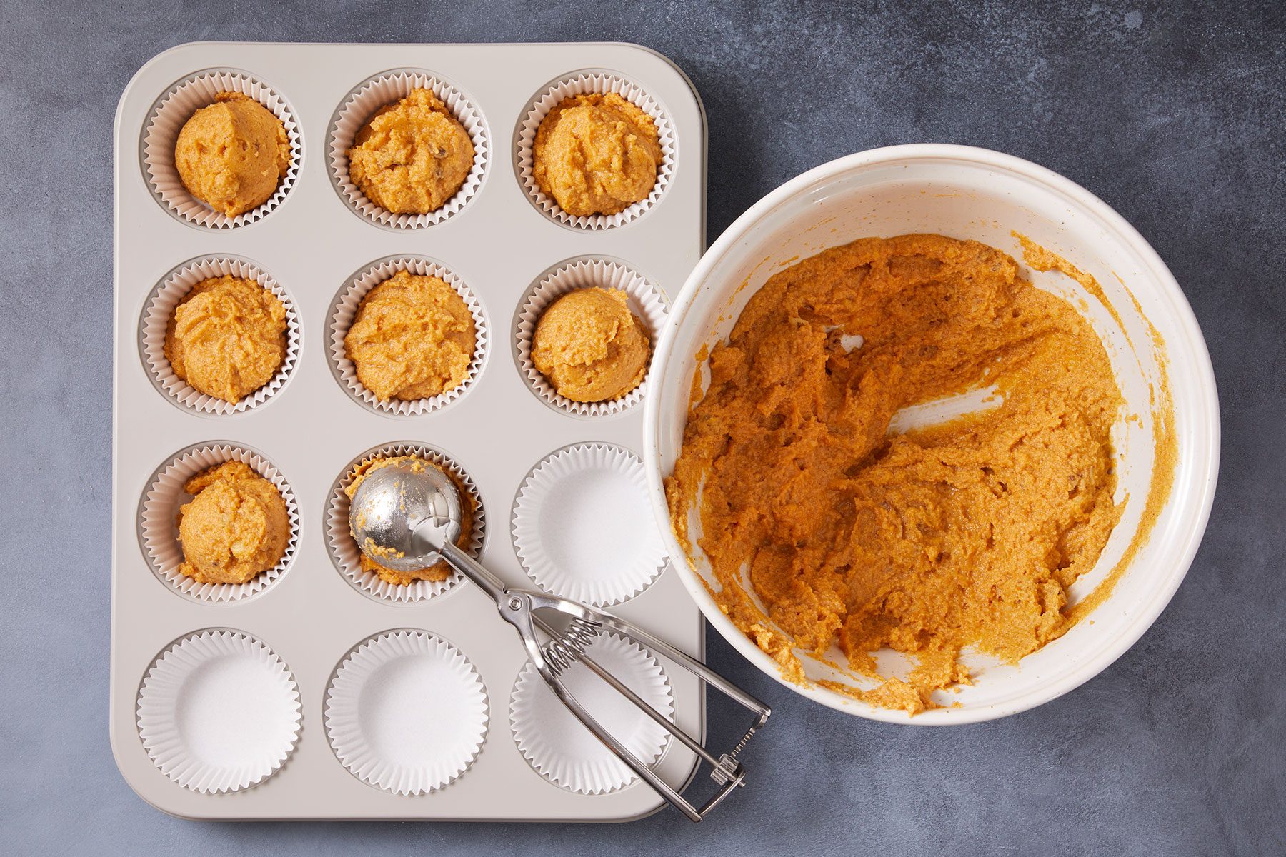 Lining 18 muffin cups with paper liners and dividing the batter evenly among them and filling it with muffin batter.