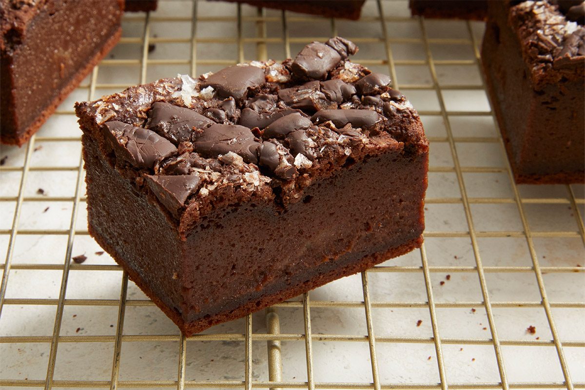 Closeup shot of a sliced mochi brownie resting on a cooling rack, showing its dense, chewy interior and chocolate-studded top;